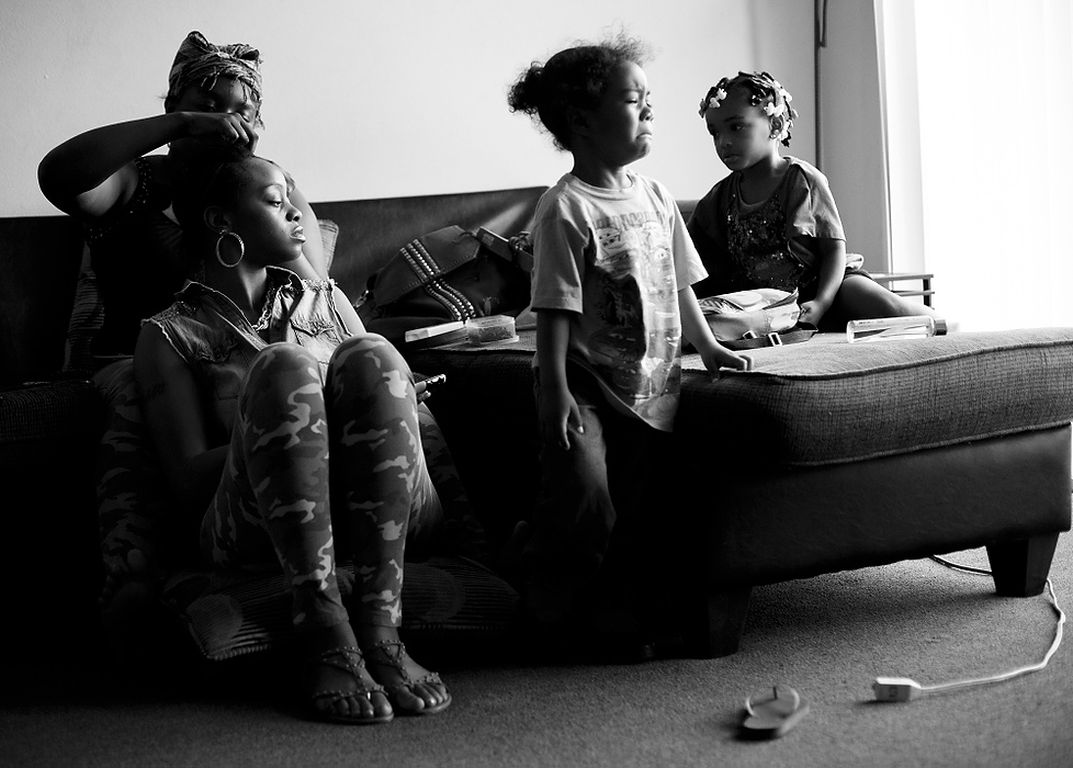 Third Place, Photographer of the Year - Large Market - Andy Morrison / The (Toledo) BladeCre'Ana Bell has her hair done by friend LaChela Benton as her son Cedyn, 2, becomes upset while playing with LaChela's daughter Za'Naya Flowers, 2, at LaChela's Moody Manor apartment.