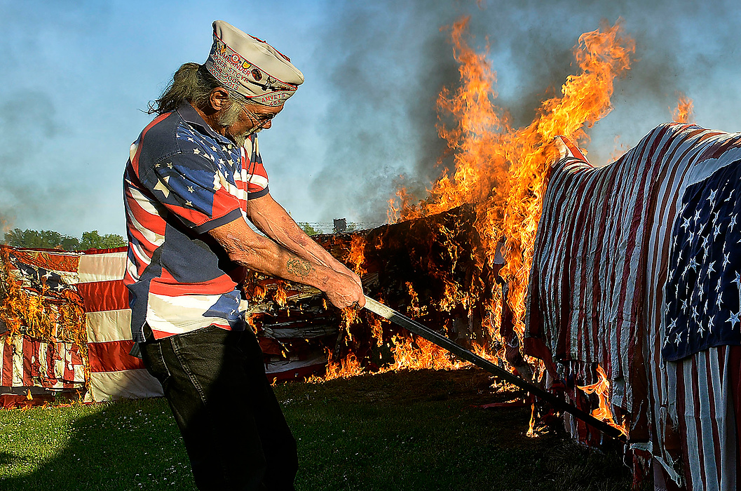 Third Place, Photographer of the Year - Small Market - Bill Lackey / Springfield News-SunRoger St. Cyr walks along the wall of American flags setting fire to them with a burning crutch Saturday during the 26th annual Flag Day flag retirement ceremony at the American Legion Post 286 in New Carlisle. During this year's ceremony, more than 5,000 worn out and faded flags were destroyed. 