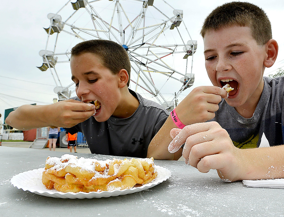 Third Place, Photographer of the Year - Small Market - Bill Lackey / Springfield News-SunPowder sugar flies in the air as Dale Miller, 12, left, and Matthew Holland, 12, enjoy a hot funnel cake on the midway at the fair.