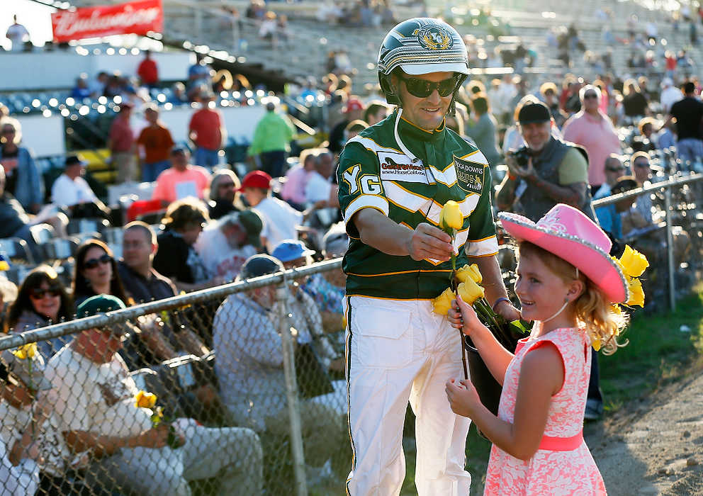 First Place, Ron Kuntz Sports Photographer of the Year - Eamon Queeney / The Columbus DispatchDriver Yannick Gingras (left) gives out a yellow rose to Lexie Delaney, 5, of Dublin, Ireland, after winning the 69th running of the Little Brown Jug at the Delaware County Fairgrounds. Yannick Gingras driving Limelight Beach won the Little Brown Jug. 