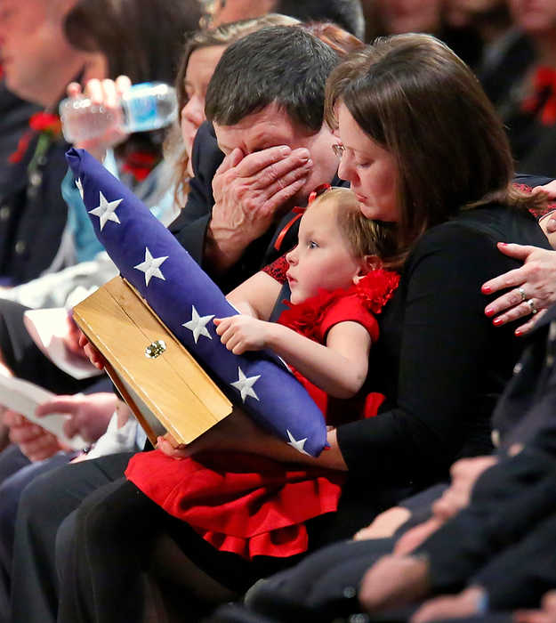 First Place, Team Picture Story  - Andy Morrison / The (Toledo) BladePaige Dickman, 3, daughter of Toledo firefighter James Dickman, holds American and Ohio flags while sitting on the lap of her mother Jamie, wife of Mr. Dickman, as she is consoled by his father Greg Dickman during the Last Alarm memorial service at SeaGate Convention Centre.