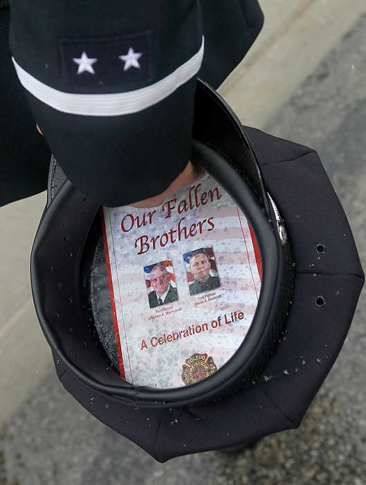 First Place, Team Picture Story  - Lori King / The (Toledo) BladeToledo firefighter Lt. Tom Bartley holds his hat as he waits for the procession for Toledo Firefighter Stephen Machcinski to pass Station 5 in downtown Toledo.