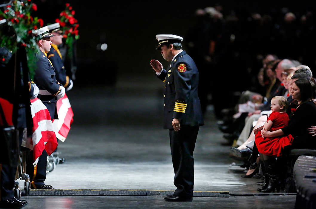 First Place, Team Picture Story  - Andy Morrison / The (Toledo) BladeToledo Fire Chief Luis Santiago salutes the casket of firefighter James Dickman, as Private Dickman’s wife, Jamie, right, holds their daughter Paige, during the Last Alarm funeral service at SeaGate Convention Centre.  Firefighters Dickman and Stephen Machcinski were killed fighting a fire.