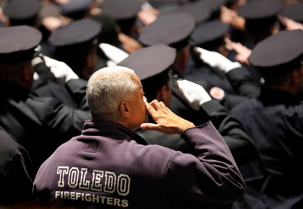 First Place, Team Picture Story  - Jeremy Wadsworth / The (Toledo) BladeA Toledo firefighter wipes a tear as others salute Thursday  during the Last Alarm memorial service for Stephen Machcinski and James Dickman, the two firefighters killed in the line of duty.