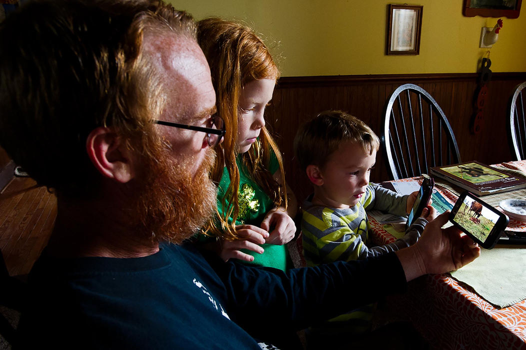 First place, Larry Fullerton Photojournalism Scholarship - Sarah Stier / Ohio UniversityAfter lunch Lilah and Harlan gather around their father, Nick Nolan, to watch a video on his cell phone of the family's cows giving birth to her calf. This calf is one of the three calves that the Nolans have on their farm in Gallipolis.  