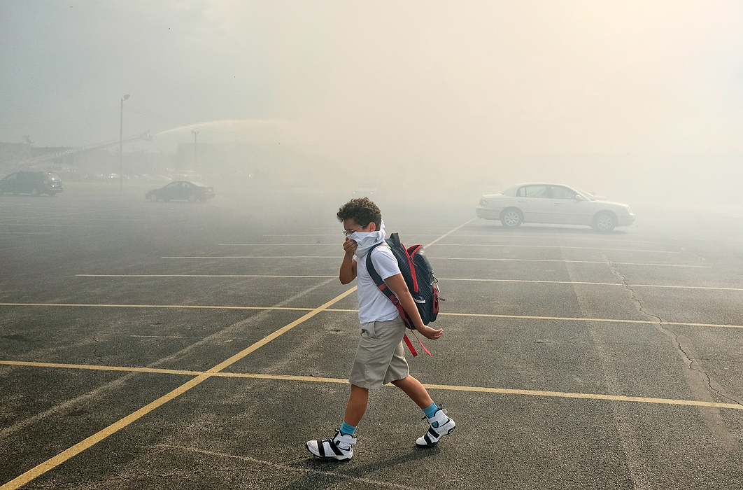 Award of Excellence, Spot News - Jeremy Wadsworth / The Blade Cameron Walker, 11, walks through the parking lot at St. Patrick's of Heatherdowns and shields himself from the smoke coming from the fire at the Andover Apartments in Toledo.