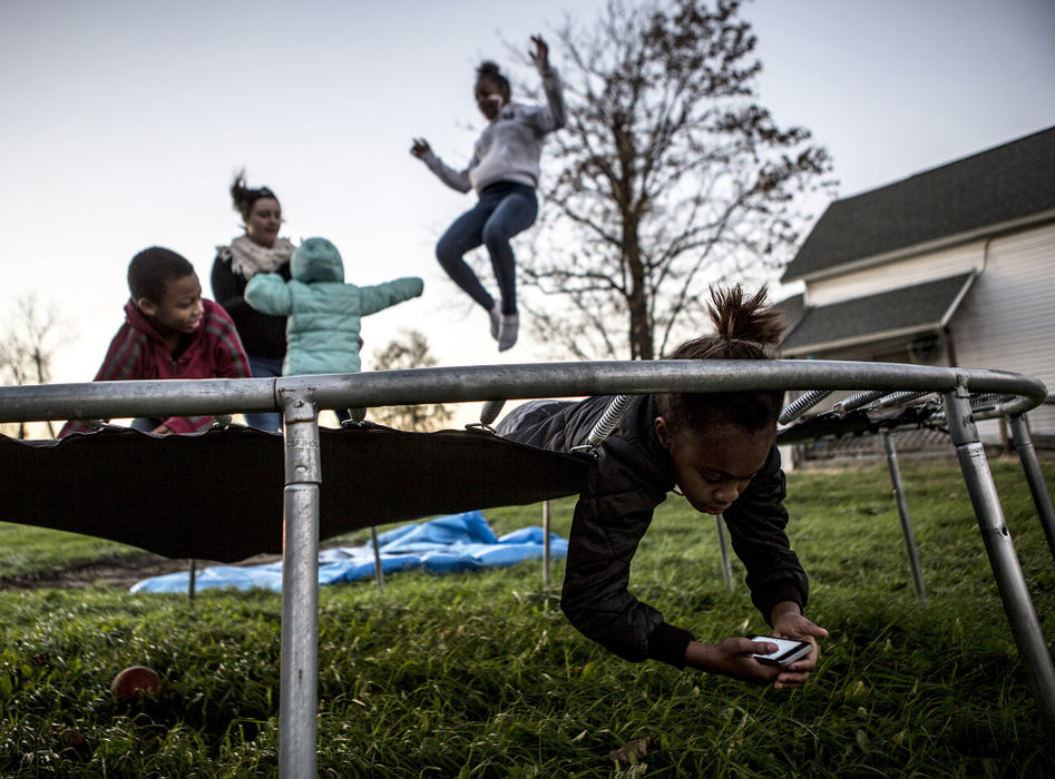 Third Place, Feature - Jessica Phelps / Newark Advocate, "Trampoline Fun"Daelesha Haile sneaks her head through a hole in the trampoline in her backyard while her sisters Daejahnae and Diamond, brother Dayvon and friend Samantha Elliot all jump around. The Haile children recently moved to Newark, Ohio from Detroit because their father believed there would be more opportunity and a quieter, safer life for them. 