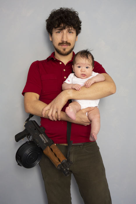 Second Place, Larry Fullerton Photojournalism Scholarship - Madeleine Hordinski / Ohio UniversityJames Rueben Tojo holds his four-month-old daughter, Ruby Hand Tojo, in Bellevue, Kentucky, April 14, 2018. Strapped around his neck is an AK-47 rifle that he often uses recreationally for target shooting.