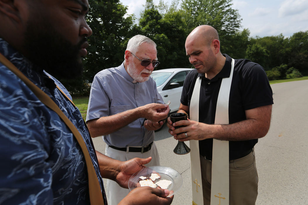 Third Place, News Picture Story - Gus Chan / The Plain Dealer, "Clergy Arrested"Rev. J.R. Rozco serves communion to Rev. John Beaty as they await arrest from Youngstown police for blocking the entrance of the Northeast Ohio Correctional Center.  