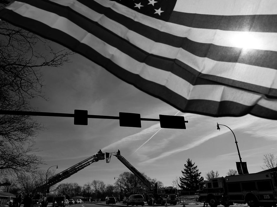 First Place, News Picture Story - Kyle Robertson / The Columbus Dispatch, "Westerville"Jeff Benninger of Sunbury holds an American flag as Columbus Fire sets up a flag on Huber Village Blvd early morning on February 12, 2018.  Westerville Police will escort the bodies of Westerville Police officers Morelli and Joering home from Franklin County Coroners office today.  