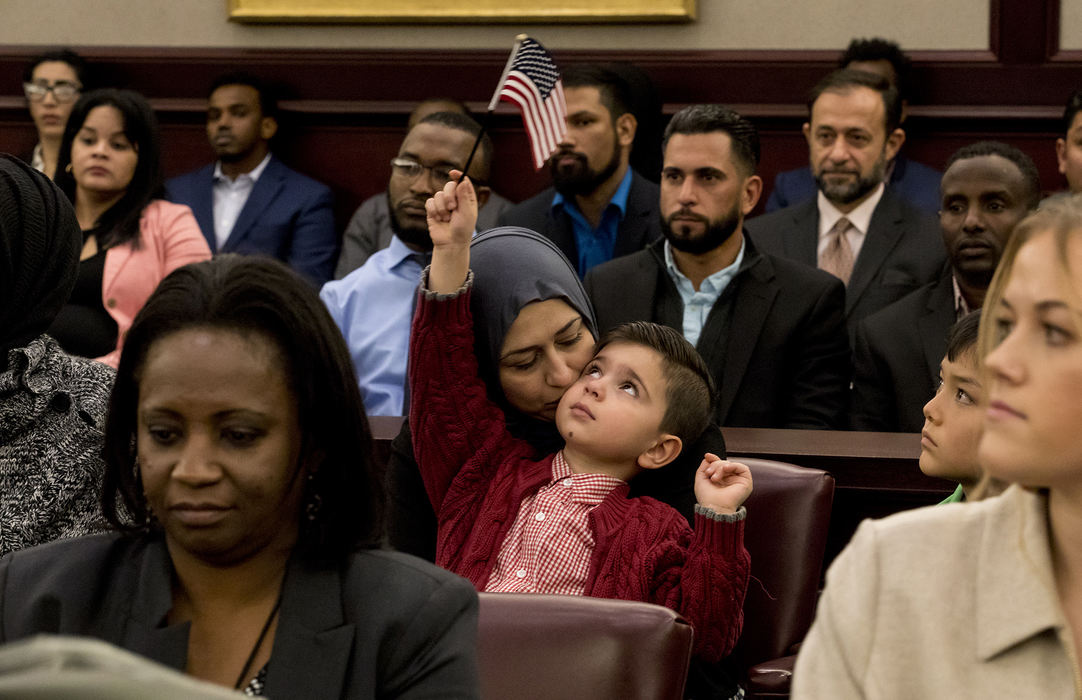 Second Place, Ohio Understanding Award - Jessica Phelps / Newark Advocate, "First Generation"Dunya Al Haek gently kisses her son Mousa as he absentmindedly waves an American flag in the air at his father's naturalization ceremony, October 23, 2018 in Columbus, Ohio. The family arrived in Ohio eight years ago on a green card. Mousa, 5,  was born in Ohio. His two older sisters, Dima and Maryam will receive their citizenship after their parents have theirs. 