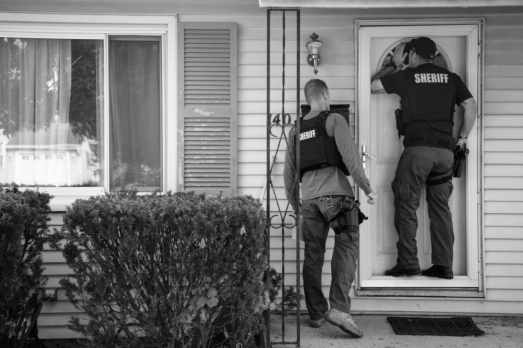 First Place, Ohio Understanding Award - Joshua A. Bickel / The Columbus Dispatch, "Wanted: Ohio's Overflowing Warrant System"Franklin County Sheriff's Office SWAT officer Nate Chalfant peers through a small window in a door to see if anyone if home while serving an arrest warrant with SWAT officer Kevin Christie, left. Often when serving warrants, officers spend more time looking for suspects then making arrests, mostly due to outdated information on the arrest warrant.