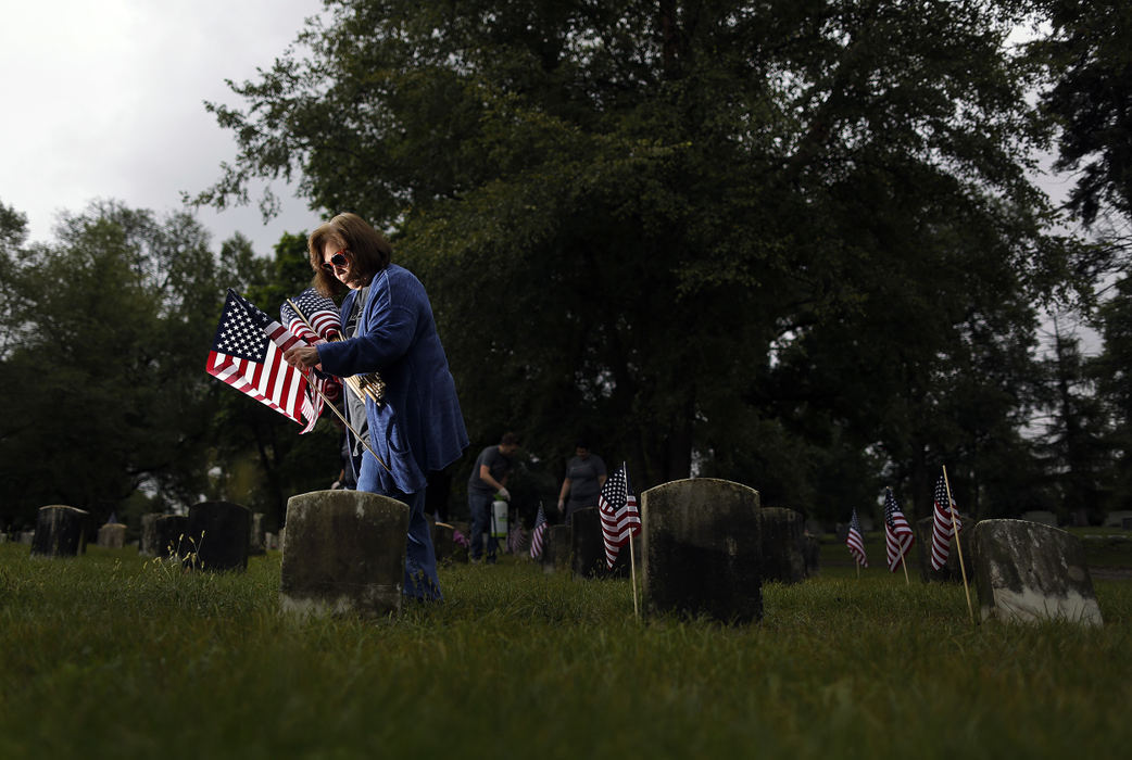 Second Place, Photographer of the Year - Large Market - Kyle Robertson / The Columbus DispatchElayne Gross of Central Ohio's AmeriCorps (Ohio Reading Corps and Ohio Math Corps) places American Flags next to headstones as other members of AmeriCorps cleans headstones in Section 71 of Green Lawn Cemetery on September 11, 2018.  The headstones were mostly of WWI veterans and some Spanish American war veterans.  Gross was a 9/11 survivor.   