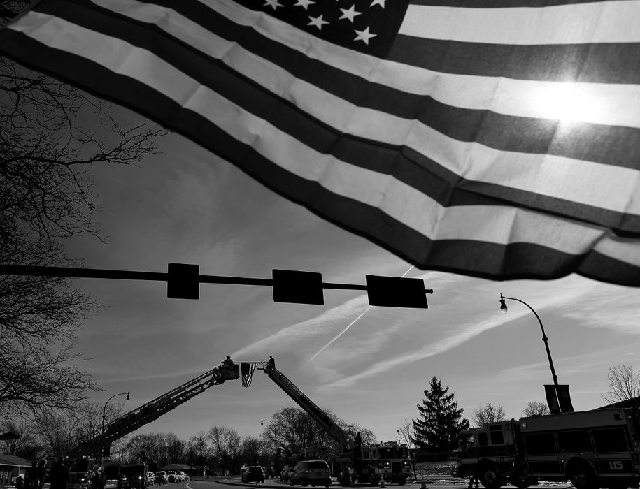 Second Place, Photographer of the Year - Large Market - Kyle Robertson / The Columbus DispatchJeff Benninger of Sunbury holds an American flag as Columbus Fire sets up a flag on Huber Village Blvd early morning on February 12, 2018.  Westerville Police will escort the bodies of Westerville Police officers Morelli and Joering home from Franklin County Coroners office today.  