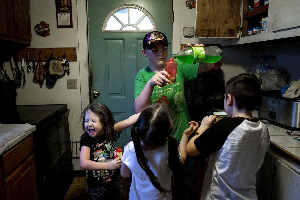 First Place, Photographer of the Year - Small Market - Jessica Phelps / Newark AdvocateAlways helping to take care of his younger siblings, Jay Crawford, braves their screams in the kitchen to pour them each a glass of soda, June 26, 2018. The Crawford, a family of eight live in a rundown three bedroom home in Newark. The landlord has been slow to fix problems as they arise, if at all.