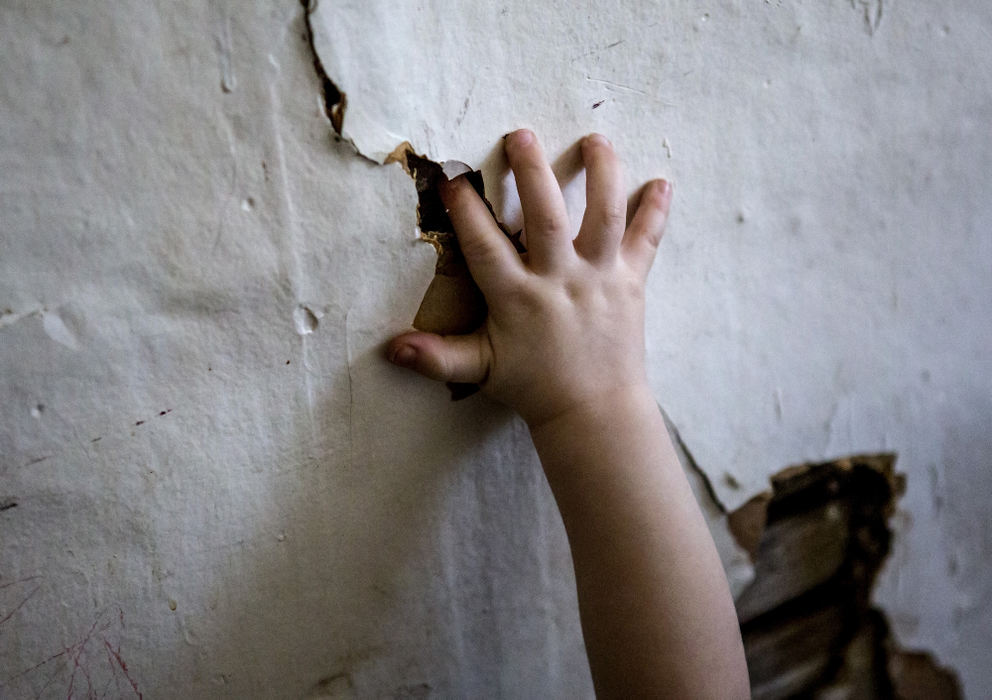 First Place, Photographer of the Year - Small Market - Jessica Phelps / Newark AdvocateTristan, 2, the youngest of the six children, curiously puts his fingers in the holes in the entry way of their home April 11, 2018. The three bedroom home, which is too small for their family, but all his parents, Melisa and Jack Crawford can afford, has a myriad of problems, including the holes and cracks in the wall from water damage. 