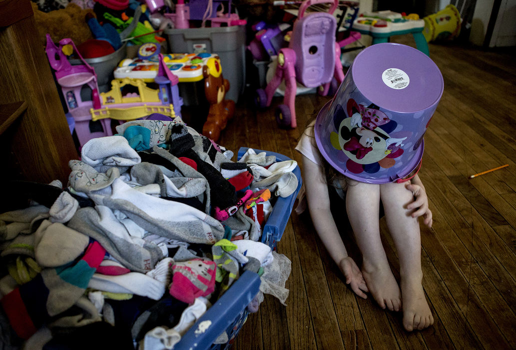 First Place, Photographer of the Year - Small Market - Jessica Phelps / Newark AdvocateSorai Crawford, 4, sits in her living room with a bucket on her head April 11, 2018. Sorai and her 5 brothers and sisters, and parents, Melisa and Jack live in a crowded 3 bedroom house on Mt. Vernon Ave. in Newark. Their landlord has been good to the family if they are a couple of days late with rent, but has also been slow fixing the holes in the wall caused by water damage and replacing the kitchen floor which is currently made of plywood. Melisa works 56 hours a week and still has trouble making ends meet for her family. 