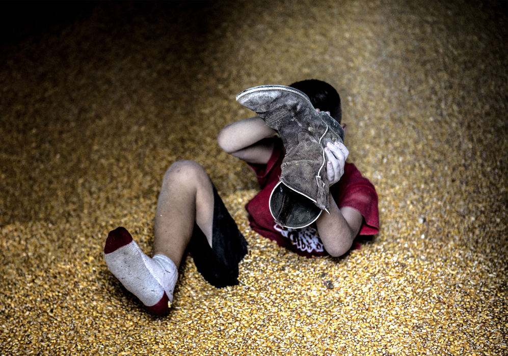 First Place, Photographer of the Year - Small Market - Jessica Phelps / Newark AdvocateBryce Hollenback dumps dried corn kernels out of boot after playing in the grain bin while his mom, not pictured, carefully watched to make sure he didn't get hurt July 18, 2018. Bryce lives on a the family farm with his parents Andy and Mamie and his older brother Arthur. Buying the farm was always Andy's dream and he says he has been fortunate to be successful so far in the 15 years they have owned the property. 