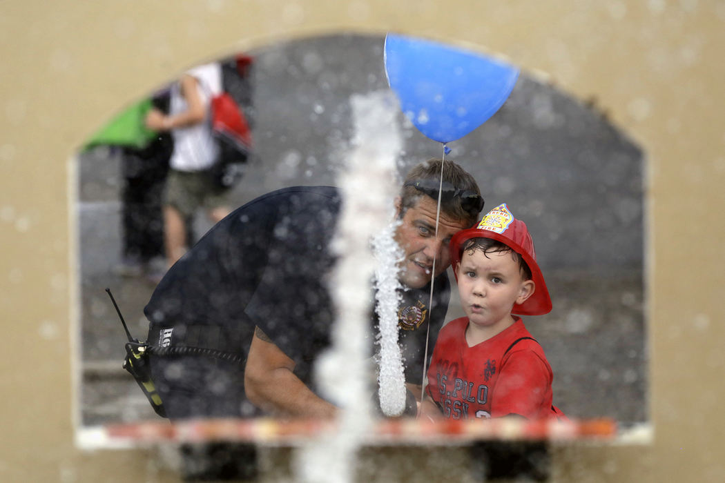 , Photographer of the Year - Small Market - Shane Flanigan / ThisWeek NewspapersLt. Kevin Childs, with Truro Township Fire Department, helps Joseph Finnerty II, 5, of Reynoldsburg, spray some targets at a firefighter game during the fourth annual National Night Out event, hosted by the Reynoldsburg Division of Police, on Aug. 7, 2018, in Reynoldsburg, Ohio.