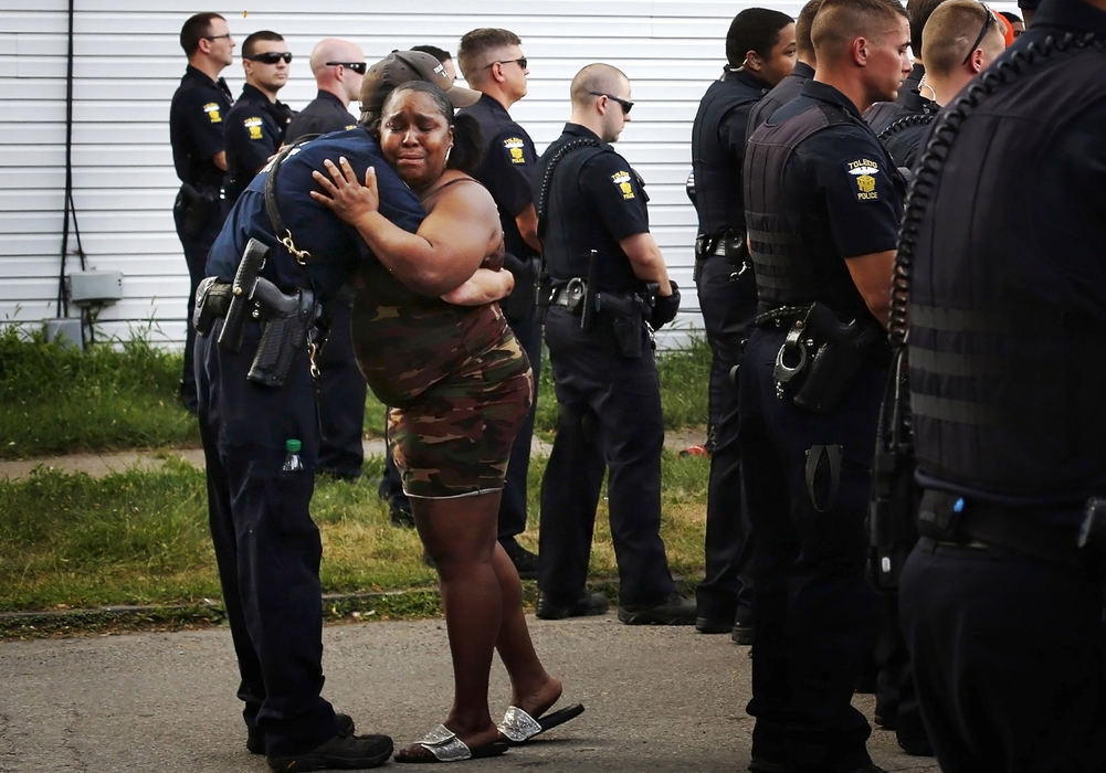 Third Place, Spot News - Samantha Madar / Central Michigan University, "Embrace "A Toledo pice officer hugs a grieving woman near the scene of an officer involved shooting near Lagrange and Hudson streets in Toledo on July 27, 2018. The shooting, which ended the life of Lamar Richardson, who was killed by a Toledo police officer, caused a large crowd to gather at the scene. 