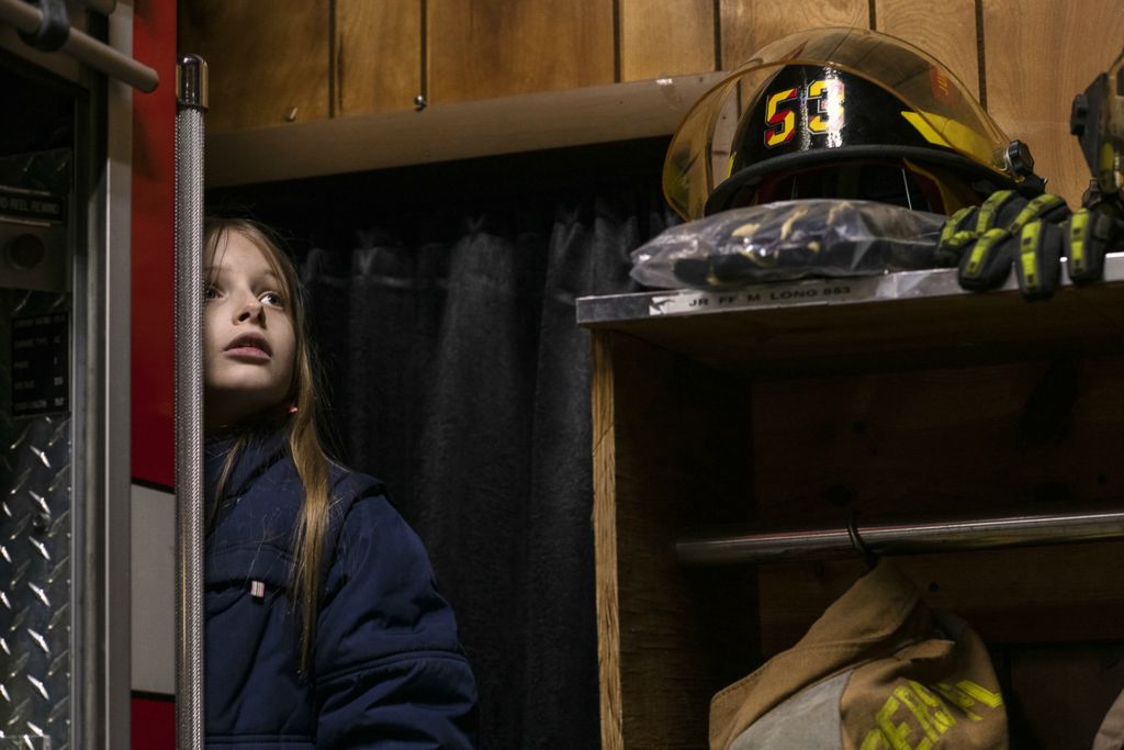 First Place, Chuck Scott Student Photographer of the Year - Gaelen Morse / Ohio UniversityNevada Johnson, 9, of Tuppers Plains, looks out from behind a firetruck at pictures of firefighters on the adjacent wall inside the Tuppers Plains Volunteer Fire Department on February 2, 2019. Both Johnson's mother and father are volunteer firefighters with TPFD, and Nevada often explores when they spend time in the firehouse together as a family.