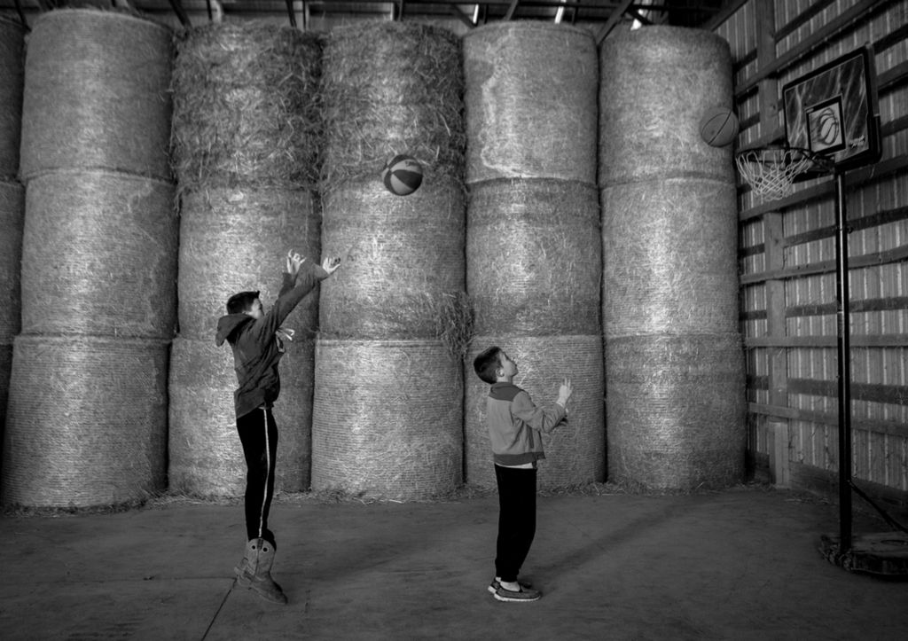 Third Place, Feature - Jessica Phelps / Newark Advocate, “Barn Basketball”Brothers Arthur and Bryce Hollenback play basketball in the barn on their family farm in Utica, Ohio. The brothers love the freedom that comes with being able to play outside and create their own adventures. Their parents love the sense of responsibility and independence they are learning. 