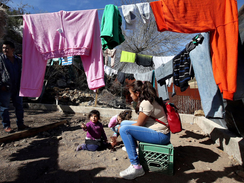 Second Place, News Picture Story - Lisa DeJong / The Plain Dealer, “Border Wall”Dulce Belen Garcia Nara, 17, her daughter Genesis Elisa Santos Garcia, 2, far left, both fleeing Guerrero, Mexico, pass the time underneath the laundry line at the La Roca shelter next to the border wall. Child on far right is another child at the shelter, Ashlee Valentina Sereno Diaz, 4, who is fleeing violence in Honduras. The organization Cruzado Fronteras runs this shelter and volunteers assist migrants trying to enter the United States. La Roca currently houses about 30 families and is typically their last stop before they wait in line to seek asylum in the United States. Some languish for months here, stranded in U.S. immigration purgatory. 