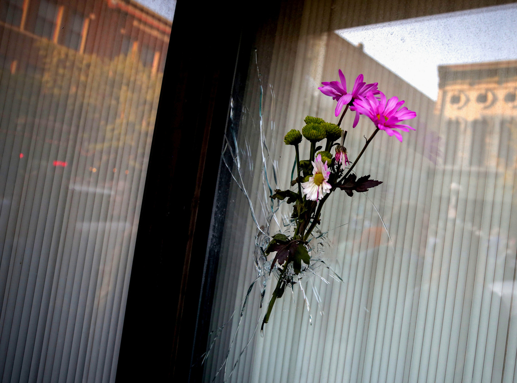 First Place, News Picture Story - Kurt Steiss / The Blade, “Dayton Shooting”Flowers sit in a bullet hole in a building's window during an evening vigil held in the Oregon District in Dayton, Ohio, on Sunday, Aug. 4, 2019.