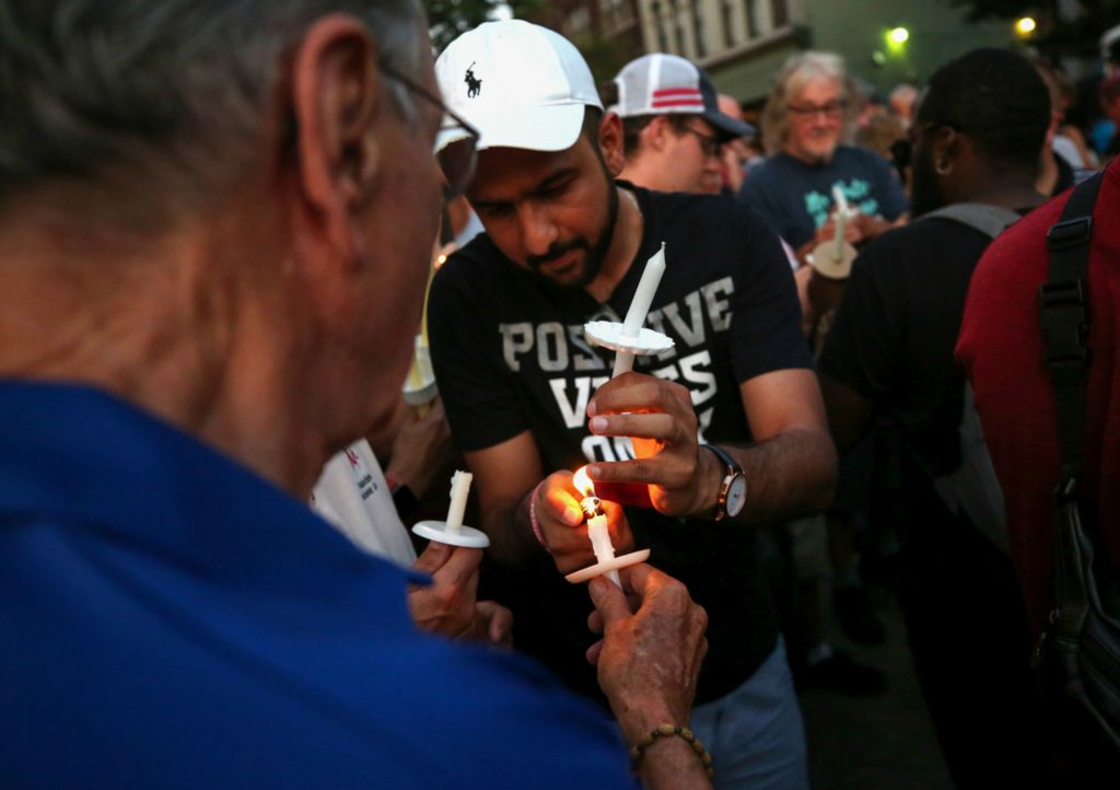 First Place, News Picture Story - Kurt Steiss / The Blade, “Dayton Shooting”A man lights another man's candle during an evening vigil held in the Oregon District in Dayton, Ohio, on Sunday, Aug. 4, 2019. 