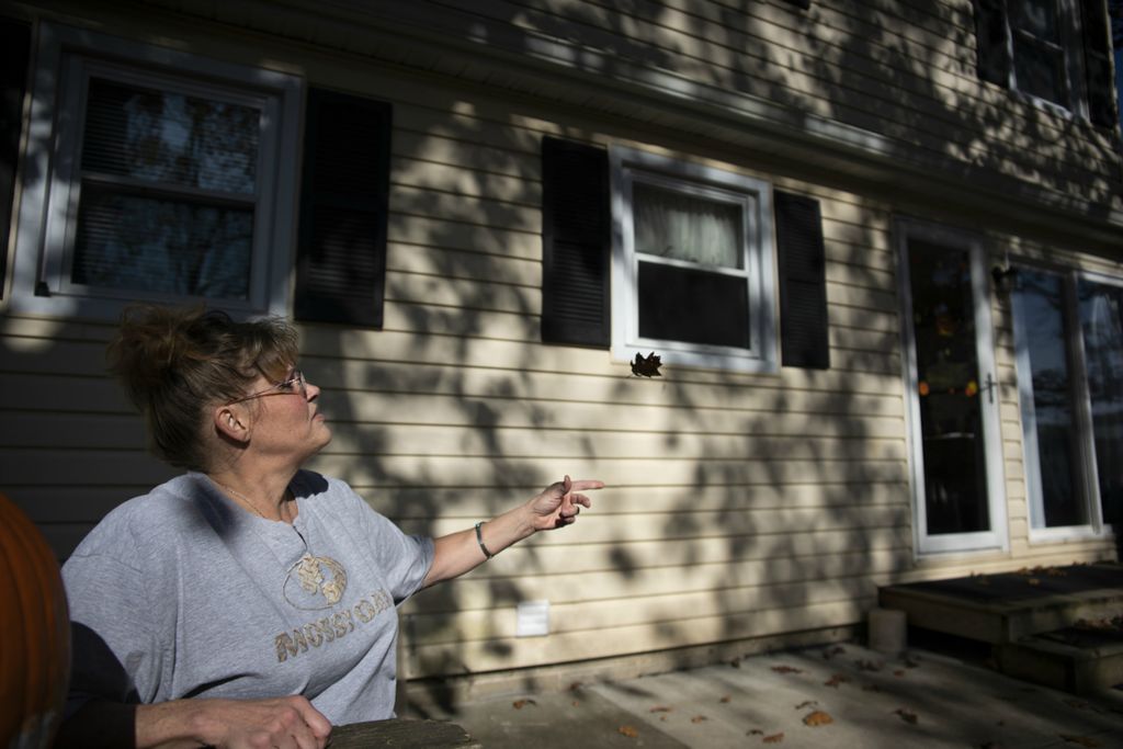 First Place, James R. Gordon Ohio Understanding Award - Erin Burk / Ohio University, “Serenity Grove”Teresa Murphy, a former resident, throws a leaf while sitting outside the Serenity Grove house. After moving out, she spent time working in the house before moving on to new things. 