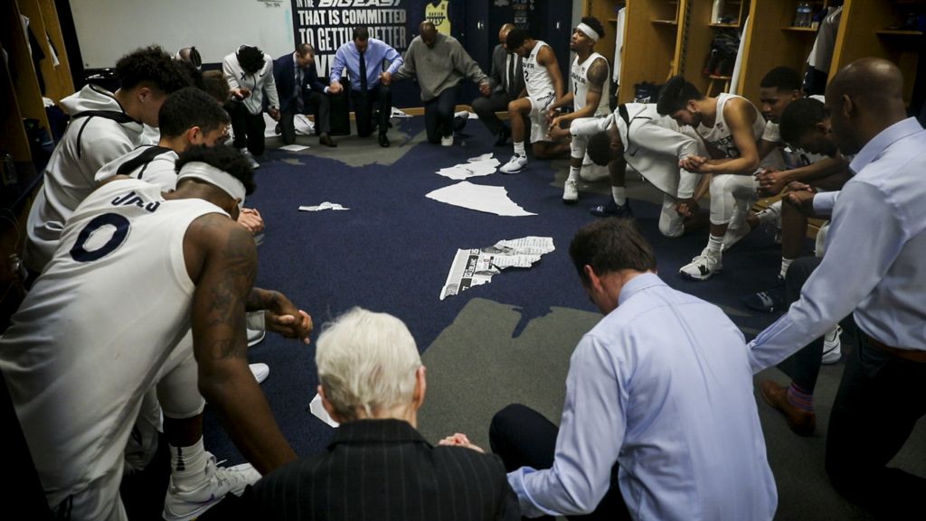 First Place, Photographer of the Year - Large Market - Meg Vogel / The Cincinnati EnquirerSr. Rose Ann Fleming prays the Our Father with the Xavier Men's Basketball team after their victory over Georgetown Wednesday, January 9, 2019 in the locker room at the Cintas Center. Fleming prays with the team after every home game.