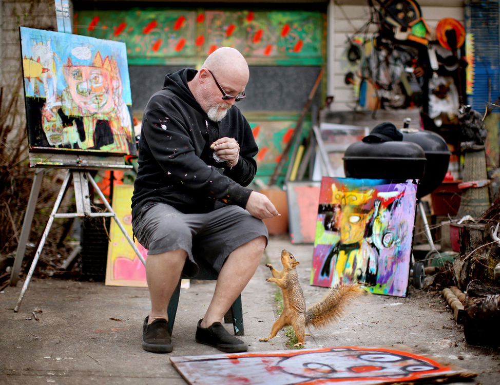 Second Place, Photographer of the Year - Large Market - Lisa DeJong / The Plain DealerArtist Scott Pickering, 58, feeds peanuts to Sprungy, his backyard squirrel, at his colorful home in the Slavic Village neighborhood. Pickering, a community leader who has lived here since the 1980s, is determined to stick it out in this economically challenged area. In the aftermath of the foreclosure crisis, the number of vacant homes rose to more than 1,300. At last count, there were 758 vacant structures in the Broadway-Slavic Village neighborhood. Pickering has tried to do his part, painting many of the boarded up properties in Slavic Village with his whimsical artwork. 