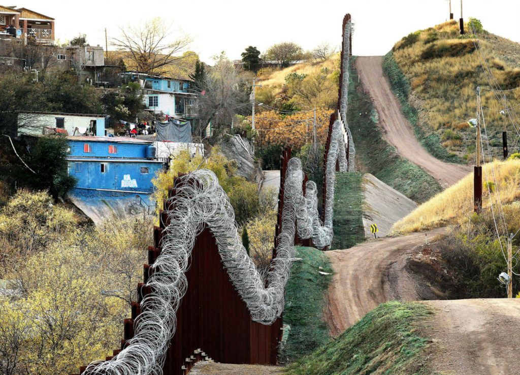 Second Place, Photographer of the Year - Large Market - Lisa DeJong / The Plain DealerThe border wall between Nogales, Sonora, Mexico, and Nogales, Arizona, rises between 18 and 24 feet tall. It is made of vertical, triangular steel beams and topped with coils of razor wire. On Feb. 2, just days after this picture was taken, the U.S. Army began installing razor-sharp concertina wire all the way to the ground after orders came from Washington D.C. to fortify the wall. Nogales, Arizona Mayor Arturo Garino was furious about the dangerous addition of the razor wire and explained it was not needed. Garino said it makes his city look like East Berlin. Of the 1,954 miles of border between the United States and Mexico, about 580 miles already have a wall or some sort of barrier. 