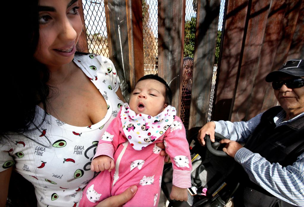 Second Place, Photographer of the Year - Large Market - Lisa DeJong / The Plain DealerThe border wall was no barrier for the Martinez family as four generations gathered on both sides of the wall around the new addition, baby Layla Morena, in Nogales, Sonora, Mexico. New mother Dania Morena, left, holds her daughter Layla Morena during a visit with her mother, Flora Martinez, who peeks through the fence on the Nogales, Arizona side. Flora Martinez, who traveled from Phoenix, is meeting her new granddaughter for the first time today. On far right is Dania Morena's grandfather, Clemente Martinez, father of Flora Martinez. The family used to be able to stretch their arms through the four-inch gap in the beams for an awkward hug, but last year the U.S. welded a heavy steel mesh to the walls in Nogales. Martinez escaped violence in Mexico and lives in the U.S. on a work visa. She wants her family to seek asylum to also be freed of constant fear. President Trump's immigrations policies make it nearly impossible for them  to seek asylum, separating the families from each other's daily lives for years now.