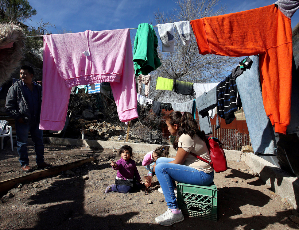 Second Place, Photographer of the Year - Large Market - Lisa DeJong / The Plain DealerDulce Belen Garcia Nara, 17, her daughter Genesis Elisa Santos Garcia, 2, far left, both fleeing Guerrero, Mexico, pass the time underneath the laundry line at the La Roca shelter next to the border wall. Child on far right is another child at the shelter, Ashlee Valentina Sereno Diaz, 4, who is fleeing violence in Honduras. The organization Cruzado Fronteras runs this shelter and volunteers assist migrants trying to enter the United States. La Roca currently houses about 30 families and is typically their last stop before they wait in line to seek asylum in the United States. Some languish for months here, stranded in U.S. immigration purgatory. 