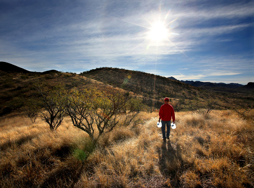 Second Place, Photographer of the Year - Large Market - Lisa DeJong / The Plain DealerUnderneath the searing sun, volunteer Ricardo Osburn, 68, walks with fresh gallons of water towards a water drop in the Sonoran Desert in Arizona in January. "We just want to eliminate deaths in the desert," Osburn said. "That's what it is all about - saving lives." Osburn, a member of the Tucson Samaritans, works with Ohio volunteers to load up 72 gallons of water and drives for hours through the unforgiving desert landscape near Coyote Well in South Pima County at an elevation of 4,000 feet. A couple of times a week, the Samaritans leave food, water and blankets on well-traveled migrant trails. Today, Osburn checks on eight water stations and makes sure 12 gallons of water are left under milk crates. 