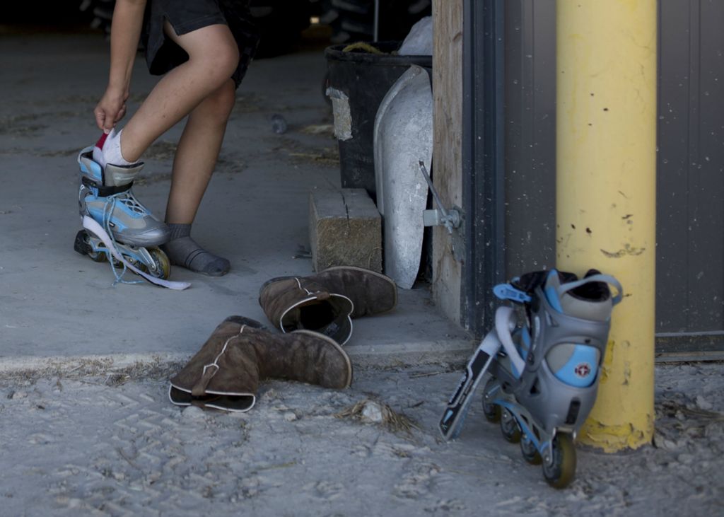 First place, Photographer of the Year - Small Market - Jessica Phelps / Newark AdvocateBryce slips off his cowboys boots and replaces them with roller blades in the one of the barns on the family farm, July 19, 2018. Growing up on a family farm in rural Ohio has offers a freedom to the Hollenback boys while also instilling in them a sense of self pride and responsibility. 