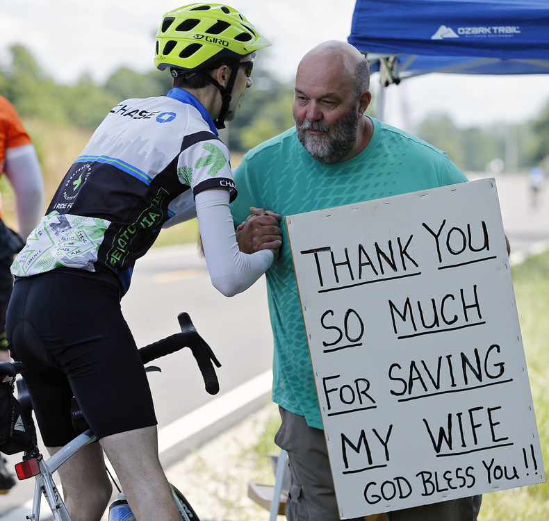 First Place, Ron Kuntz Sports Photographer of the Year - Kyle Robertson / The Columbus DispatchRider Eric Tippett shakes the hand of Chris Horton while holding a sign that thanked bicyclists for contributing to the ability for his wife to receive life-saving chemotherapy. Horton has made a memorable impression on riders, often evoking emotion and giving them inspiration to finish out the 100-mile ride during the 11th Pelotonia on August 3, 2019.