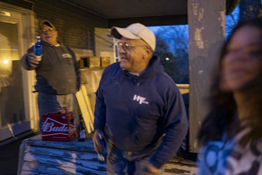 Third Place, Chuck Scott Student Photographer of the Year - Lauren Santucci / Ohio UniversityLarry and Gary Rush laugh with Erica Mayle outside of a friend’s house on the village’s main street. When the weather warms up, locals cluster on Chesterhill’s main street to enjoy each other’s company or share beers after work.  