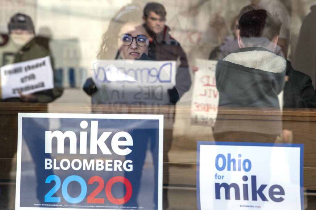 Third Place, Election 2020 - Gaelen Morse / Ohio University, “Bloomberg Campaign”A young Bloomberg Campaign volunteer looks out at protestors with a grimace from the campaign office in Athens.