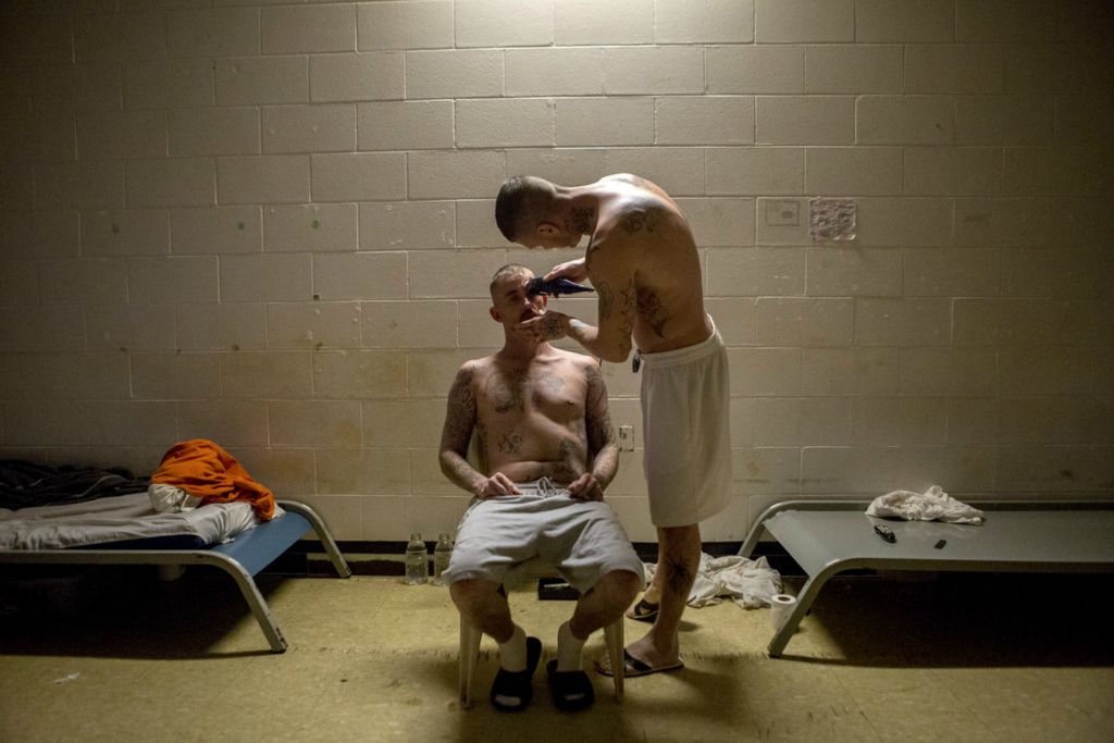 Second Place, Feature - Jessica Phelps / Newark Advocate, “Hair Cut”Justin Yates (right) trims Eldon Church Junior's hair in the former recreation room of the Coshocton County Justice Center in January, 2020. Due to overcrowding, the room has been converted to house cots for 10 inmates. 