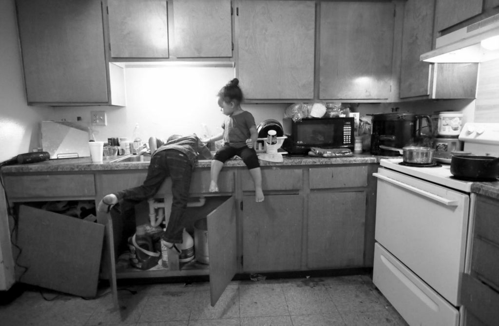 Award of Excellence, Feature - Amy E. Voigt / The Blade, “Tapwater ”Anthony Gaston (left) takes a drink of water from the tap while his youngest sister Avery Gaston watches in the kitchen at their home in Ravine Park Village on September 21, 2020. The two were helping their mother, Amber Lewandowski, cook dinner while she took a moment to herself in the living room and let the children mind themselves. Unlike many families who stay on the wait list for public housing, Ms. Lewandowski said there was a place available for her within 60 days. She was relieved when she got the call notifying her she was approved.  “When I first moved in I fell in love with it instantly,” she said.