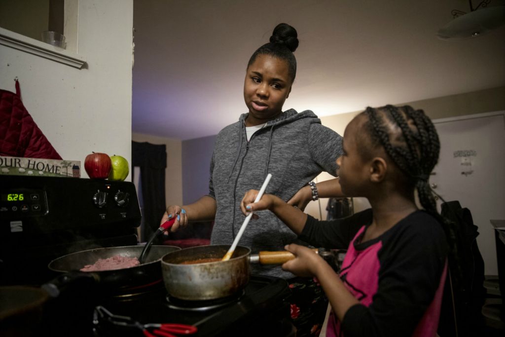 Award of Excellence, Feature Picture Story - Meg Vogel / The Cincinnati Enquirer, “Renters”Page Berry makes dinner with the help of her daughter Ajaunae, 8, in their Westwood apartment on Tuesday, February 4, 2020. Page works at the airport, moving freight on the tarmac throughout the night. She makes an extra dollar an hour by working the third shift. Page makes $17 an hour, more than she's ever made in her life, but as a single mom and only provider for her daughters, some months, it isn't enough. When she gets off work in the morning, she takes her daughters to school and then comes home for a nap. Page picks up the girls in the afternoon, helps them with homework, and makes dinner. Before she goes back to work, she drops her daughters off at her stepmom's house to sleep. This is her routine Sunday through Thursday. 
