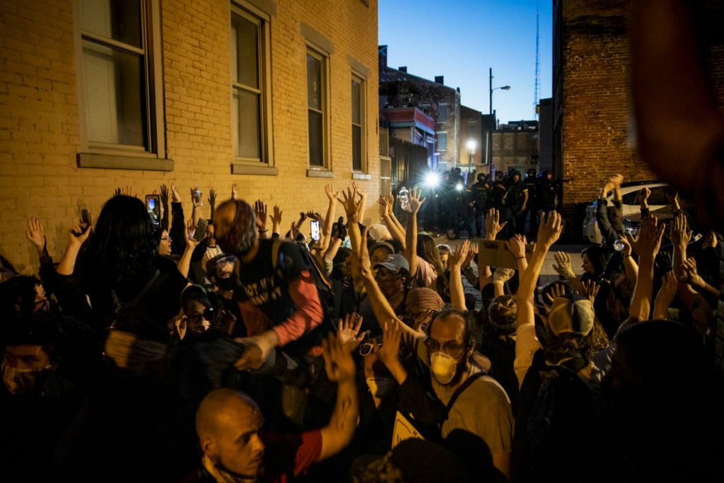 Award of Excellence, News Picture Story - Meg Vogel / The Cincinnati Enquirer, “BLM Protest”Protesters kneel in Clymer Alley with their hands up as police officers surround them after the 9 p.m. curfew in Over-the-Rhine on Sunday, May 31, 2020. This is the third night of protests in response to the death of George Floyd in Minneapolis. More than 100 people were arrested in violation of the curfew. Metro buses transported the protesters to the Hamilton County Justice Center. Many protesters complained that they were held overnight outside without food, water, or access to bathrooms.