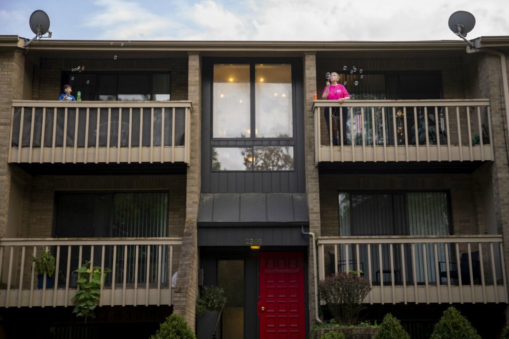 First Place, George S. Smallsreed Jr. Photographer of the Year - Large Market - Meg Vogel / The Cincinnati EnquirerDonna Kinney blows bubbles on her balcony with her neighbor Adam, 4, on Wednesday, August 12, 2020 in O’Bryonville.  Kinney is a cancer survivor who lives alone. She’s determined to stay in touch with the outside world, even if she can’t leave her apartment during the pandemic. “Being on that balcony every night gives me a feeling of freedom and more normalcy,” said Kinney, “but I never really appreciated that balcony till now.”