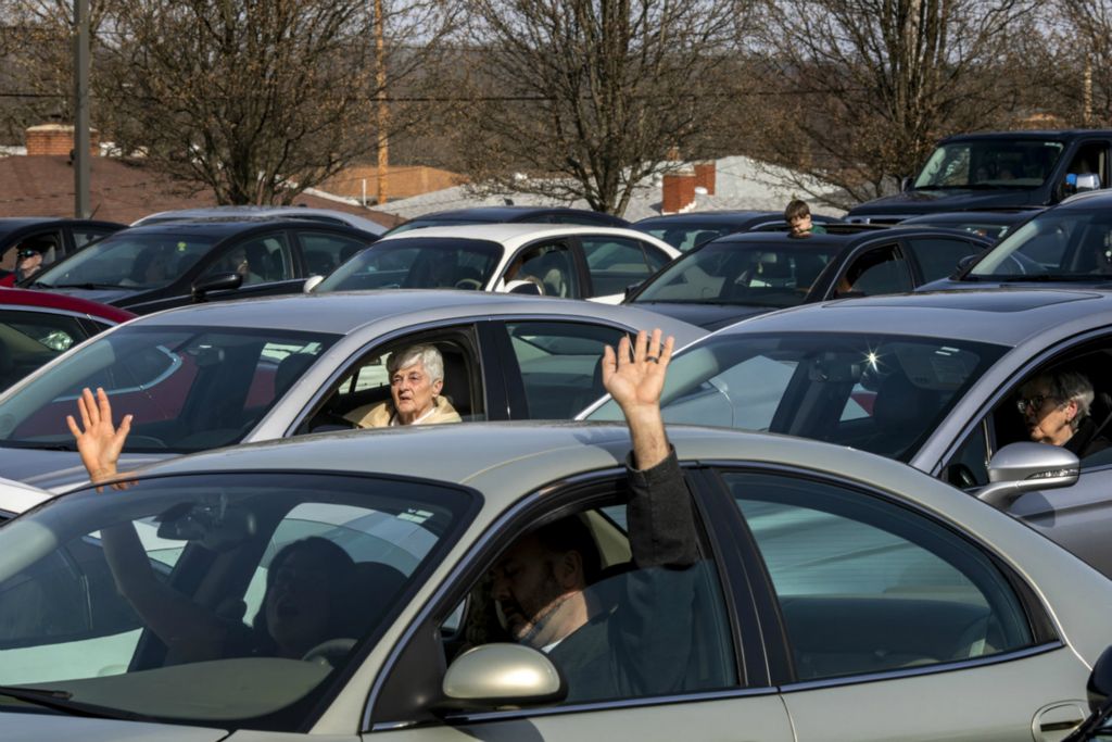 First Place, George S. Smallsreed Jr. Photographer of the Year - Large Market - Meg Vogel / The Cincinnati EnquirerCongregation members of the Lindenwald Baptist Church wave their hands outside their car windows as they sing along with the musicians at the drive-in church service in the parking lot behind Lindenwald Baptist Church on Sunday, March 22, 2020 in Fairfield. 