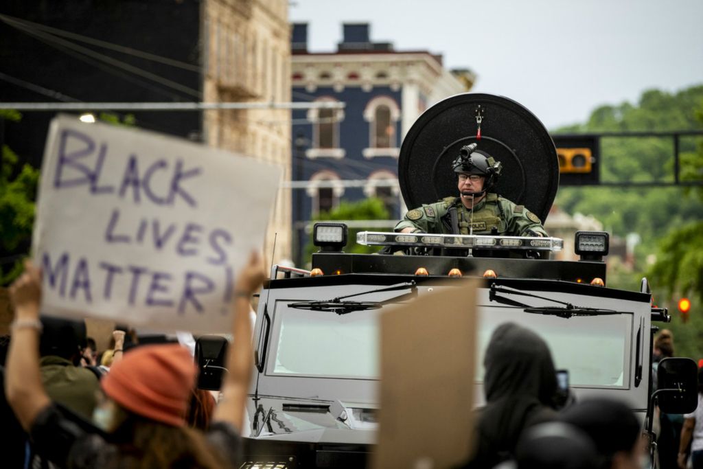 First Place, George S. Smallsreed Jr. Photographer of the Year - Large Market - Meg Vogel / The Cincinnati EnquirerProtesters walk on Main Street past an armored police vehicle outside the Hamilton County Courthouse in downtown Cincinnati on Monday, June 1, 2020. This is the fourth night of protests in response to the death of George Floyd in Minneapolis.