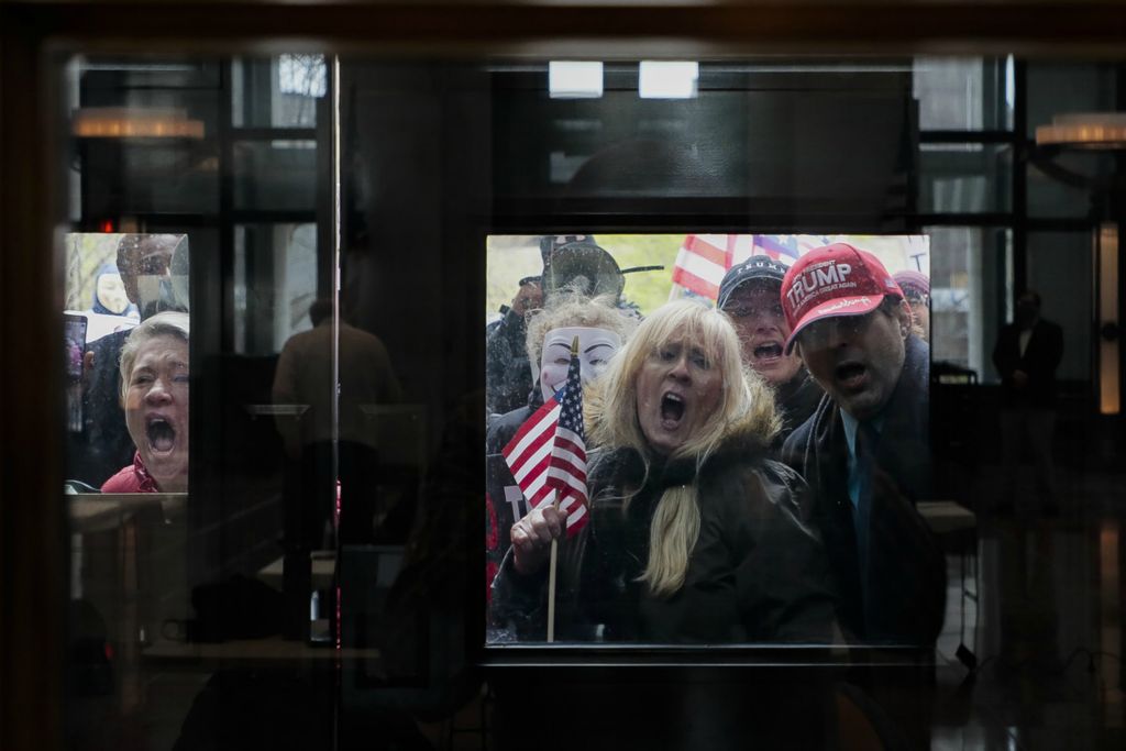 Second Place, George S. Smallsreed Jr. Photographer of the Year - Large Market - Joshua A. Bickel / The Columbus DispatchProtesters chant "Open Ohio Now!" in defiance of social distancing guidelines outside the doors to the Statehouse Atrium as news reporters listen during the State of Ohio's Coronavirus response update on April 13, 2020 at the Ohio Statehouse in Columbus, Ohio. About 100 protesters assembled outside the building during Gov. Mike DeWine's daily update on the state's response to the COVID-19 pandemic to rally against his administration's stay-at-home order and closure of non-essential businesses and schools.