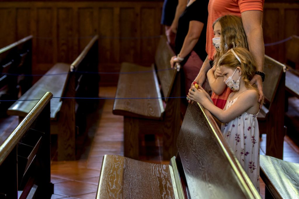 First Place, George S. Smallsreed Jr. Photographer of the Year - Small Market - Jessica Phelps / Newark AdvocateDr. Tim Miller stands with his arms around his daughters, Avery and Sydney during mass at St. Edwards in Granville on June 7, 2020. The Church started holding mass again but with some differences. Many of the pews are roped off to help keep to social distancing guidelines. All parishioners must wear face coverings and wash their hands as they enter the church and there is no hand shaking. 