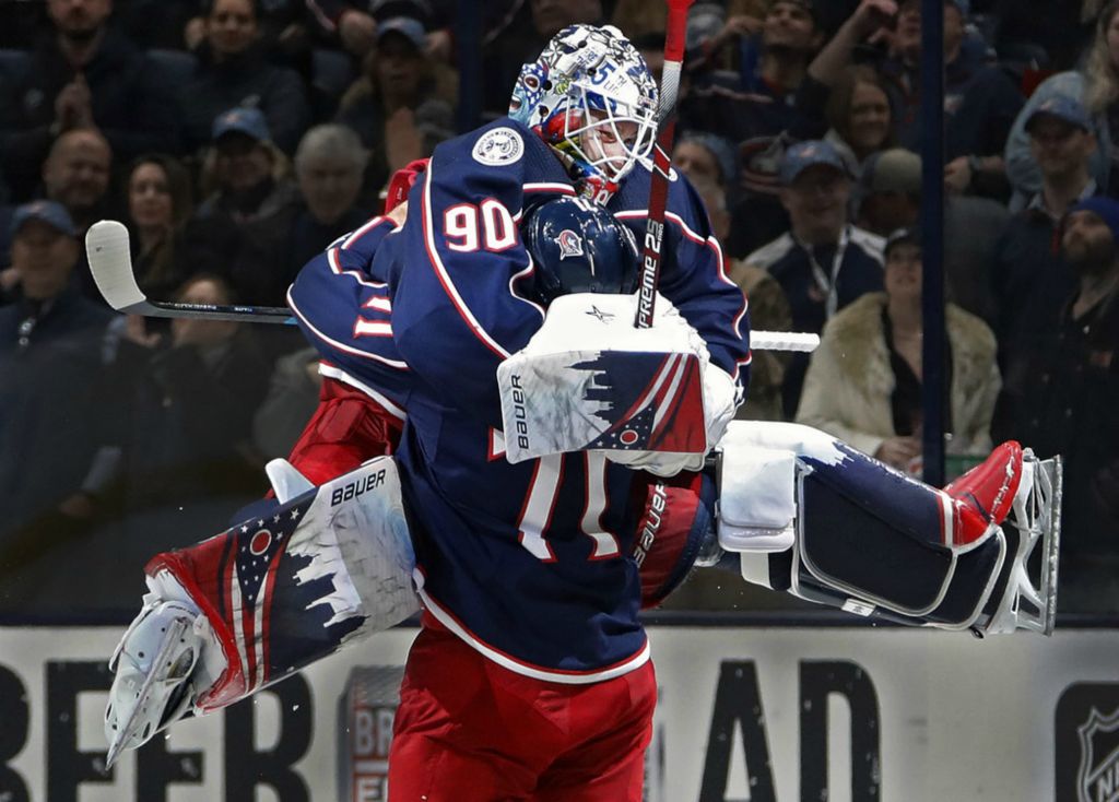 First Place, Sports Feature - Kyle Robertson / The Columbus Dispatch, “Jump”Columbus Blue Jackets goaltender Elvis Merzlikins (90) jumps into the arms of left wing Nick Foligno (71) after beating Carolina Hurricanes 3-2 in their NHL game at Nationwide Arena in Columbus on January 16, 2020. 